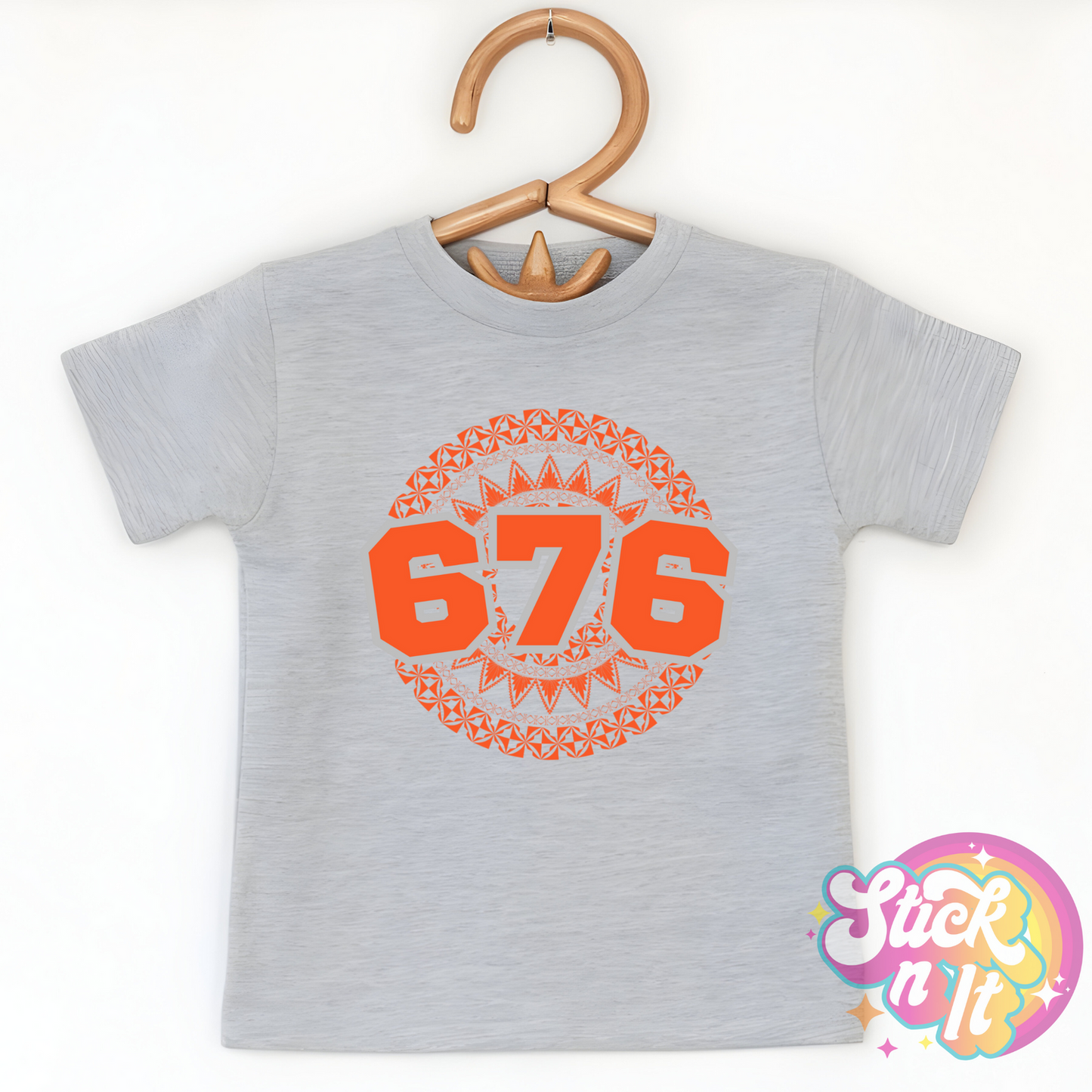 Kids size grey shirt featuring a Polynesian Tonga design with area code 676 in orange.